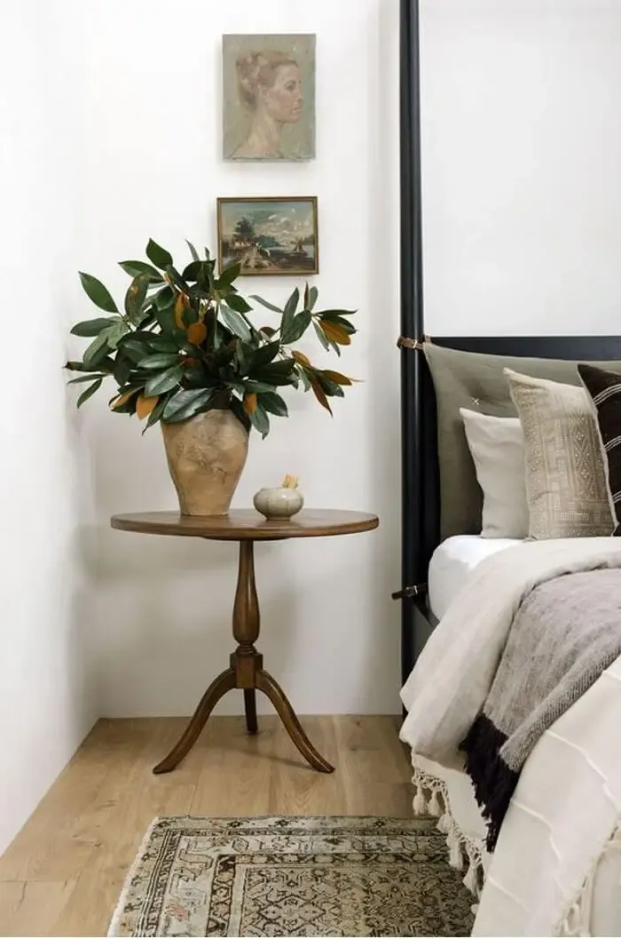 Table with magnolia leaves next to bed