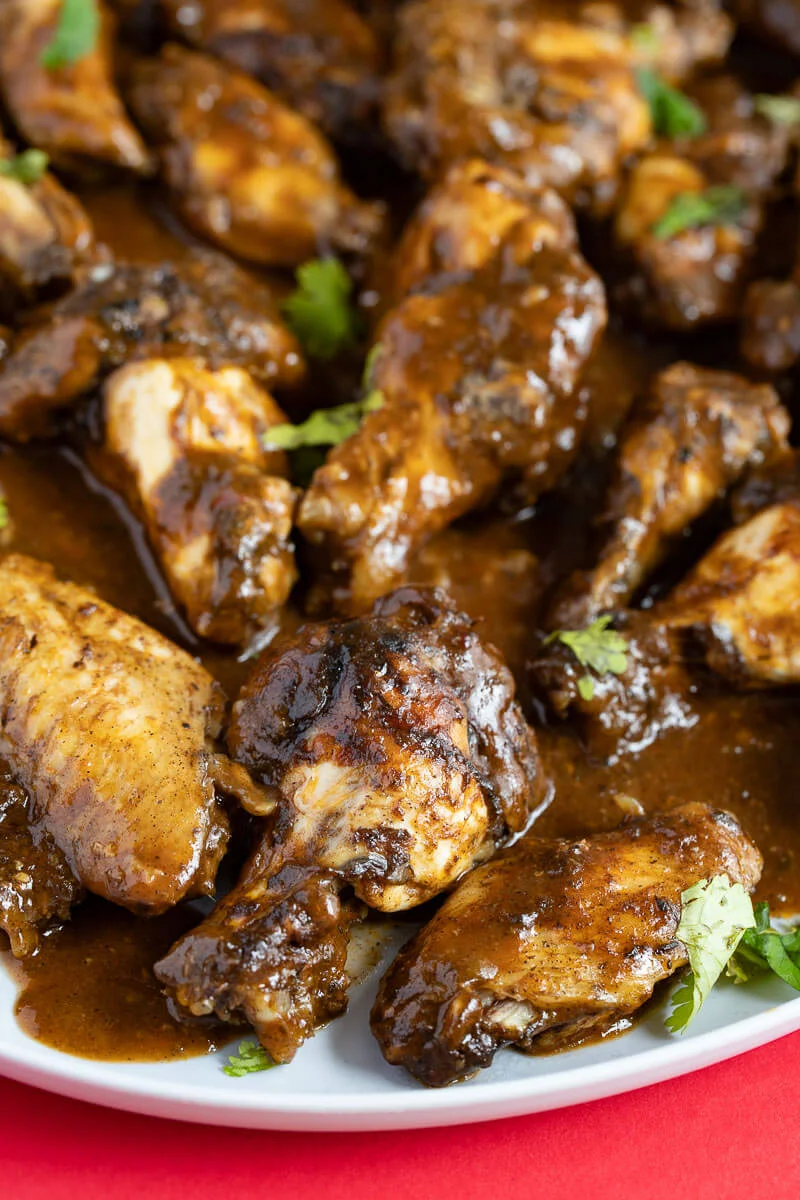 A close look at the jerk wings with sauce on a gray plate.