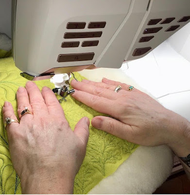 Green fabric being hand guided through a sewing machine