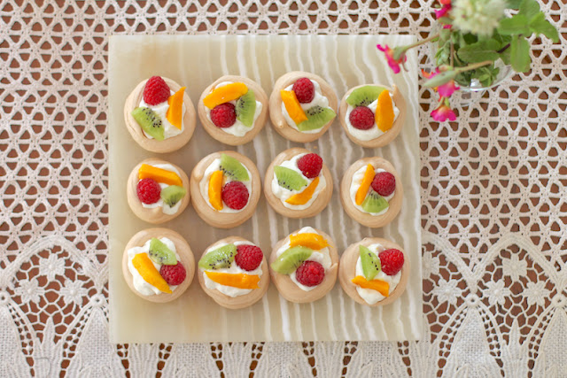 Food Lust People Love: These mini fruit-topped pavlovas are the perfect dessert for a dinner party or potluck.  The meringue bases can be made ahead of time then all you need to do is whip the cream and pop the fruit on top. No matter how it got there, pavlova is still a quintessential Australian or New Zealand dessert. A traditional fruit topping down under is passion fruit pulp but you can use whatever fruit you have on hand. Serve the mini fruit-topped pavlovas shortly after topping them as the cream will soften the meringues.