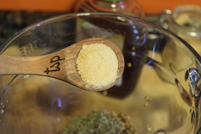 A teaspoon of garlic powder being added to a mixing bowl. 