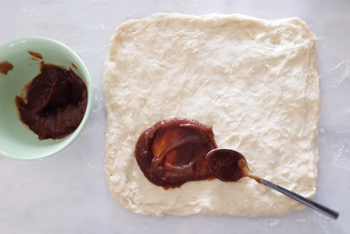 rolled dough being spread with apple butter