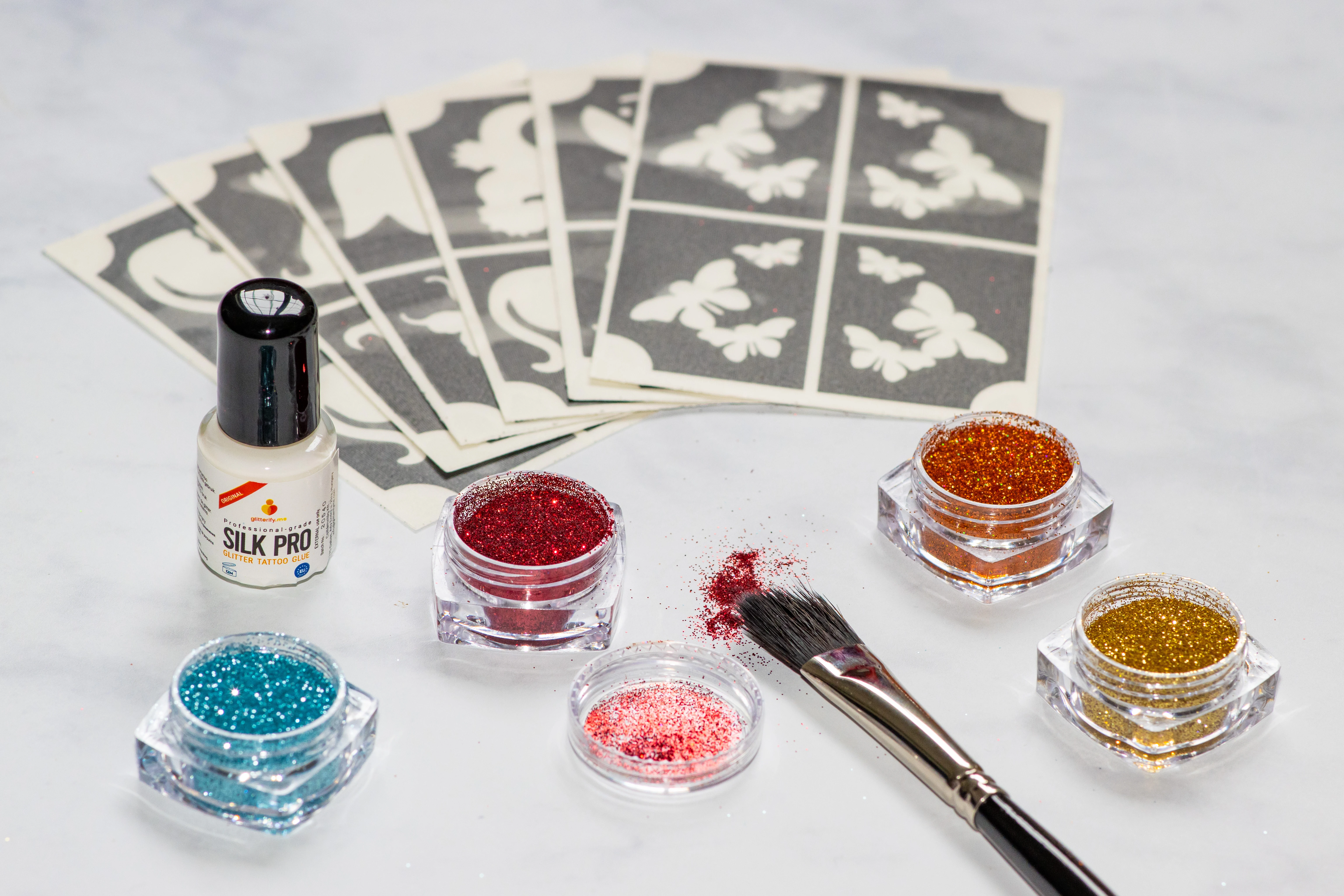 The contents of the Glitterify Me small glitter kits including stencils, 4 glitter pots, glue and applicator brush