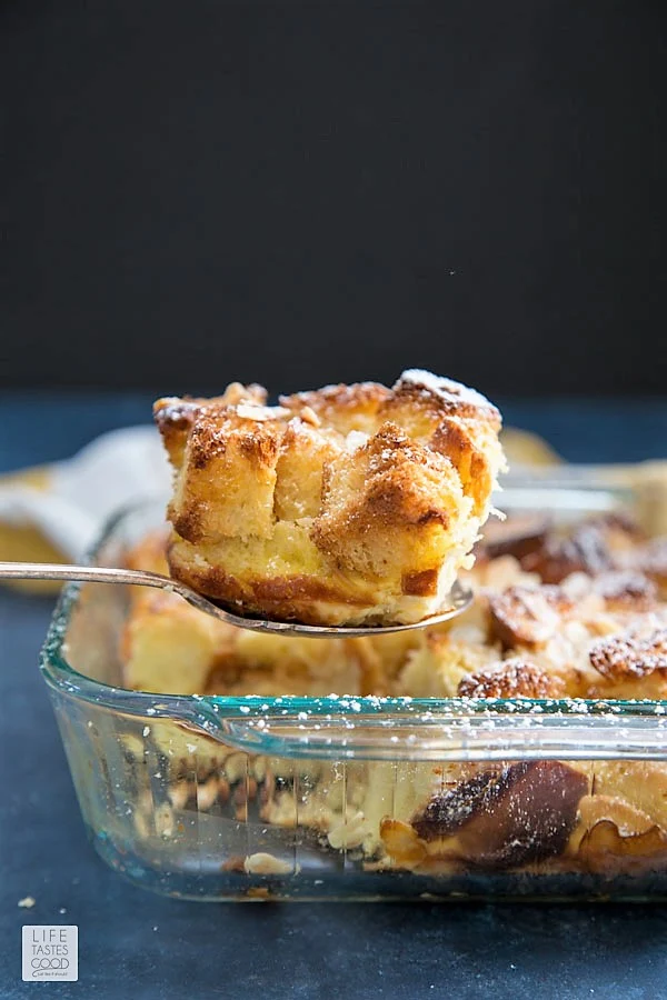 Spooning a piece of overnight french toast casserole out of the glass baking dish to serve