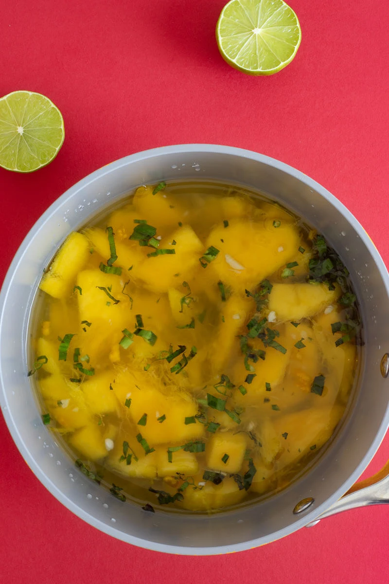 Chopped up ingredients for mango sour in the pot about to simmer.