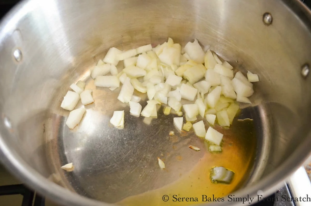 Onions with olive oil in a medium sized stainless steel pan.