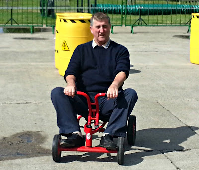 Man riding child's pedal car