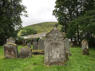 A photo of various gravestones in Durisdeer Churchyard with a larger stone in the foreground which is that of David Scott.  Photograph taken by Kevin Nosferatu for the Skulferatu Project.