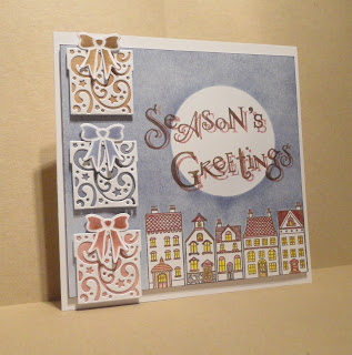 Christmas card, houses with a moon above, Season's Greetings sentiment and 3 presents on the left