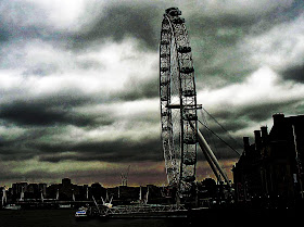 silhouette of the London Eye against a cloudy dark sky