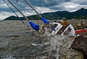 sailboat crashing on rocks in storm, sinking