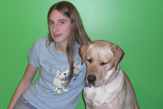 Toby still looks the same in this picture, I'm wearing my cute blue Southeastern Guide Dog shirt, it has 2 cute little puppies that made pawprints on the shirt, and are trying to climb into my pretend pocket, the green wall is the background 