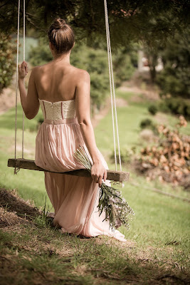 Invitada de boda con vestido color blush sentada en un columpio