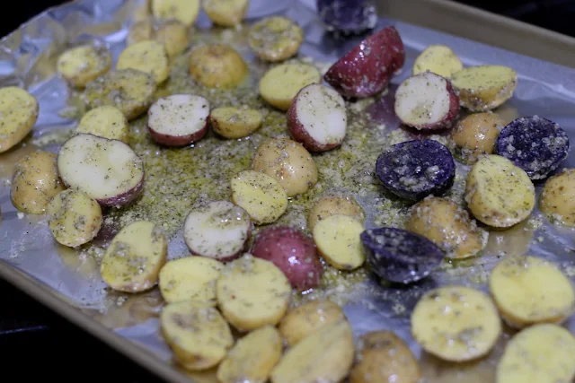 The seasoned raw potatoes on the foil lined baking sheet. 