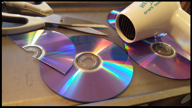 The best way I found to cut DVDs for art projects was to heat them up