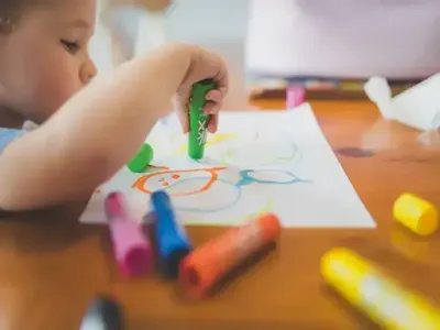 Criança desenhando com gis de cera representando o aprendizado
