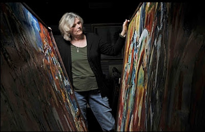 Laurie Pace standing between two large paintings.