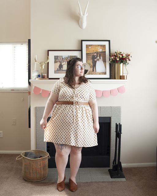 An outfit consisting of cream babydoll dress with an evenly spaced yellow floral pattern with two pussy bows and brown d'orsay flats.