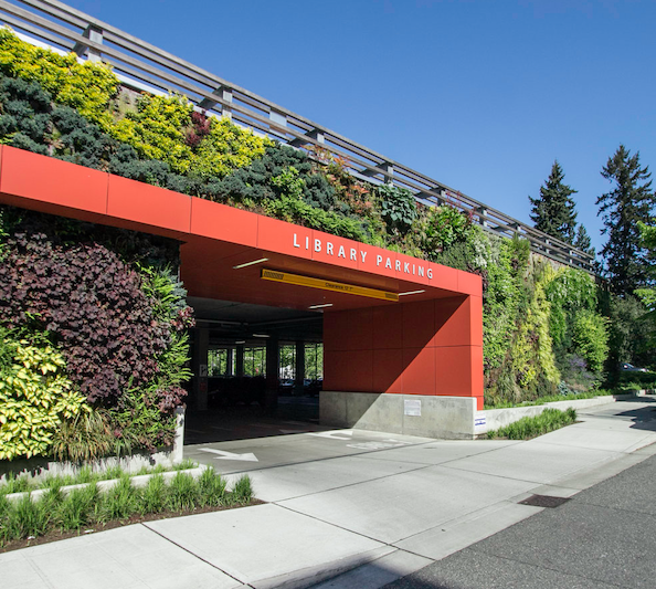 A large one-story building with a railing along the roof line. The entire facade of the building is covered with greenery.