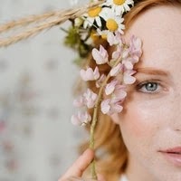 niacinamide skin benefits. Half face of a beautiful young woman who puts flowers on her hair