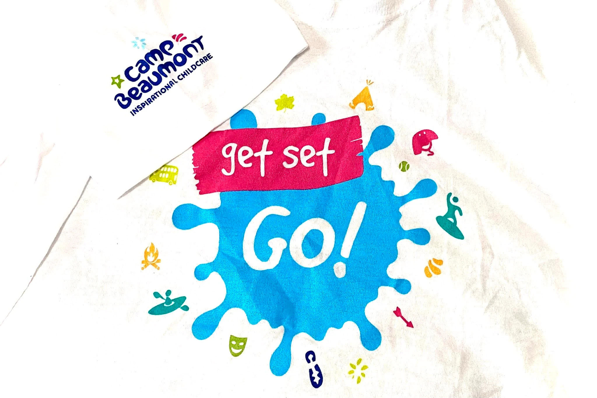 2 white t-shirts on top of each other. One has camp beaumont inspirational childcare on the sleeve, the other "get set go"