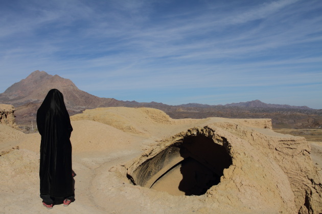 Tourist in Abaya enjoying the caving in of houses at Kharanaq, Iran