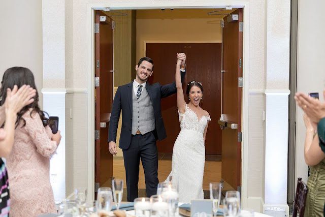 bride and groom walking into room with hands in the air in excitement