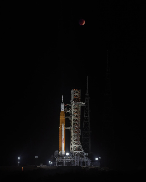 NASA's Space Launch System rocket stands tall at Kennedy Space Center's Pad 39B in Florida as a total lunar eclipse looms high above it...on November 8, 2022.