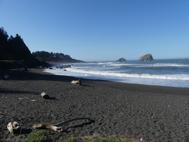 beach with many footprints and a few rocks offshore