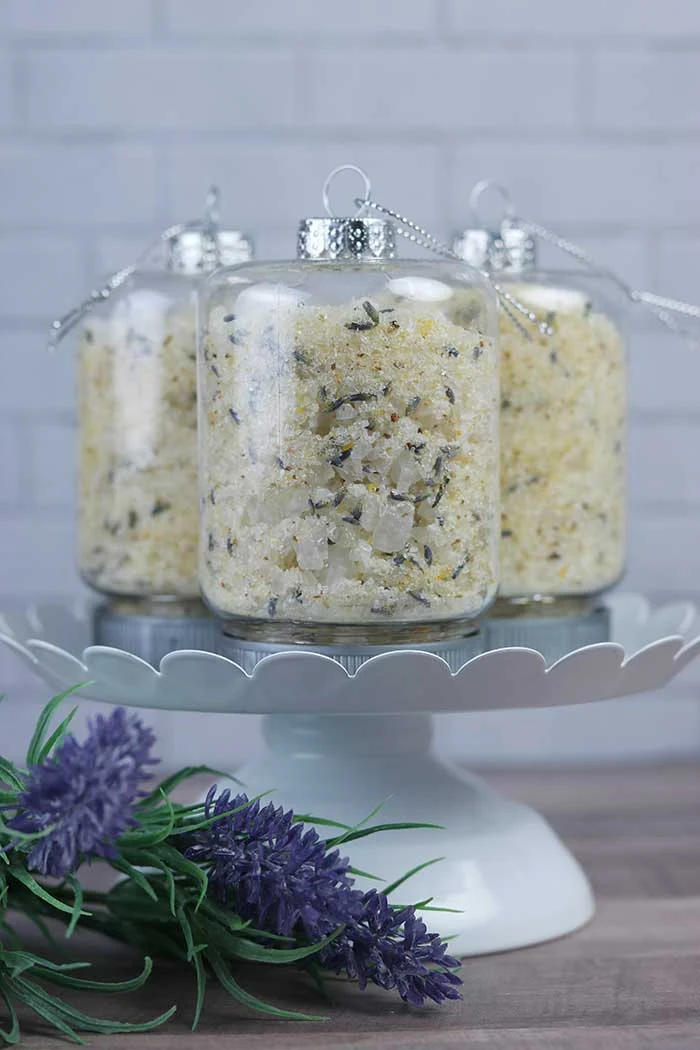 How to make an easy lemon lavender bath salts recipe with essential oils. These use aromatherapy to promote calming and stress relief and other benefits.  They are easy to make with Epsom salt, sea salt, essential oils, lavender, and dried citrus peels. This makes a great Christmas DIY gift with cute container ideas with tiny mason jar ornaments for containers. Give the gift of homemade relaxing detox herbal bath salts for Christmas. #bathsalts #diy #gift #lemon #lavender