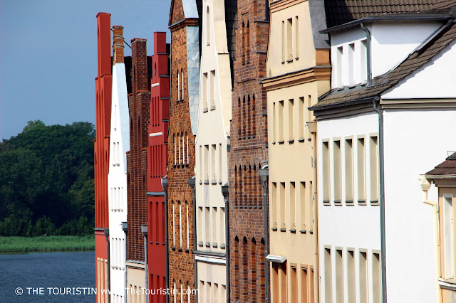 A row of olourful period facades next to a river.