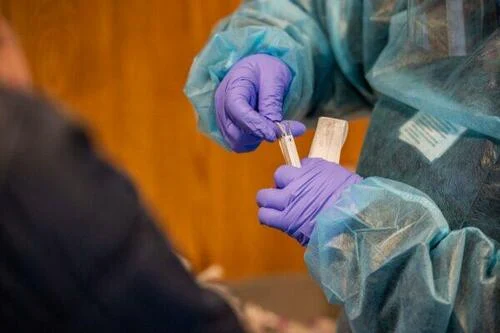 A medical worker places a nasal swab into a test tube after performing a COVID-19 PCR test at East Boston Neighborhood Health Center in Boston, Mass., on Dec. 20, 2021.