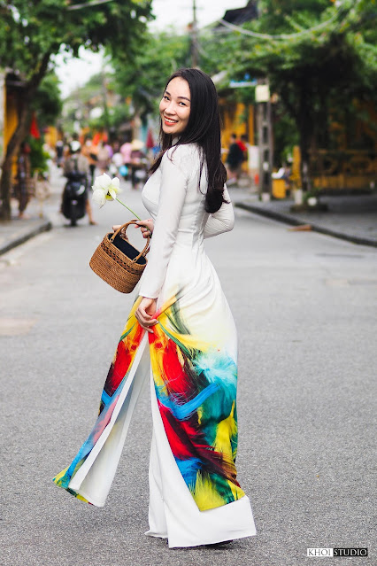Beautiful female tourists take travel photos wearing ao dai on the streets of Hoi An. Photo: Khoi Studio.