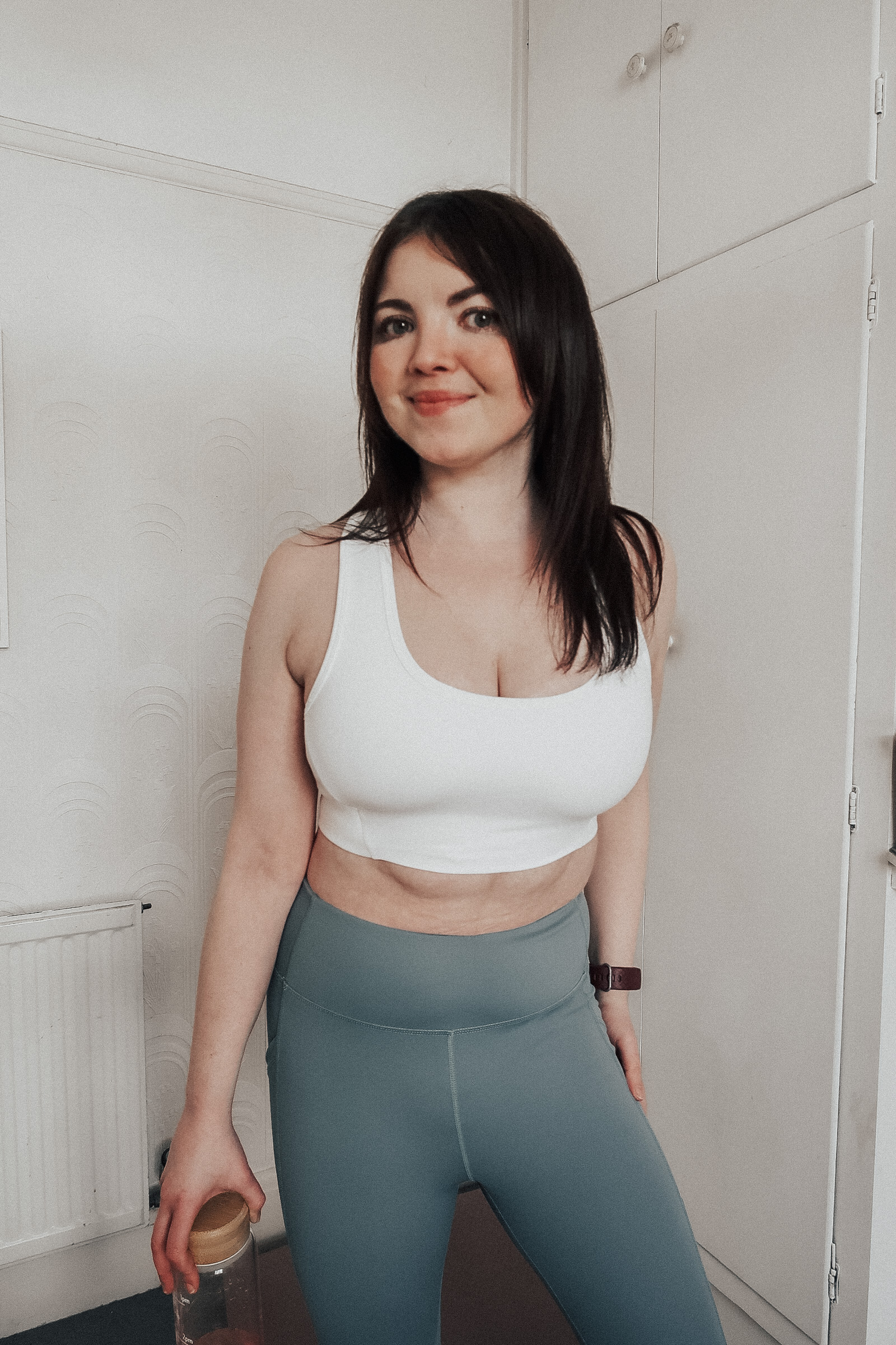 A woman wearing a white Wellicious bra and teal coloured leggings.