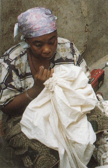A Hausa woman tying resists into cotton cloth in Kano.