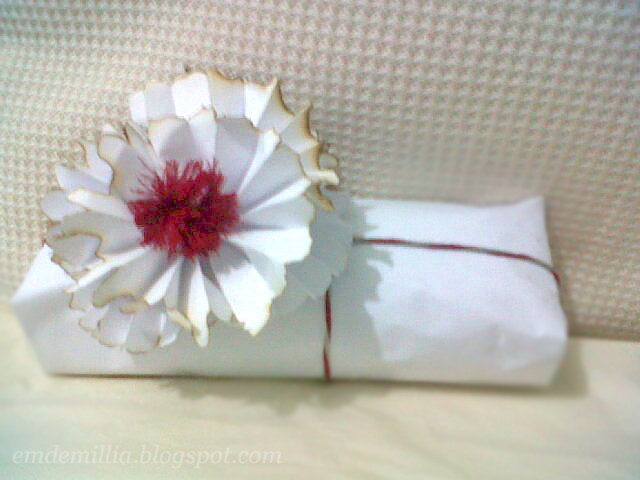 Gift with white paper wrapper and a pom-pom.