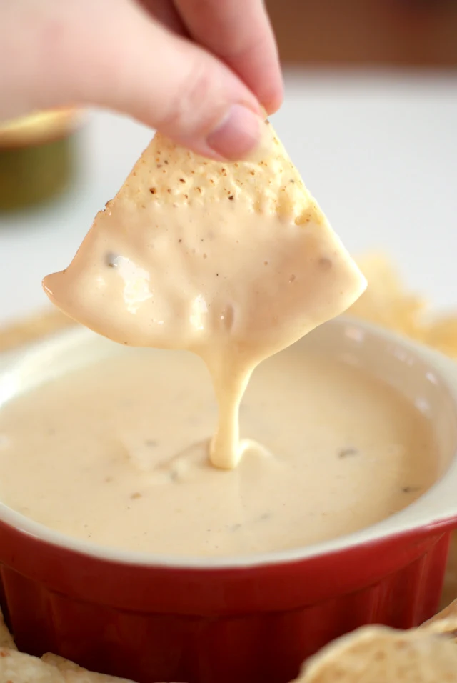 Crock Pot Queso Blanco Dip dripping off of a tortilla chip.