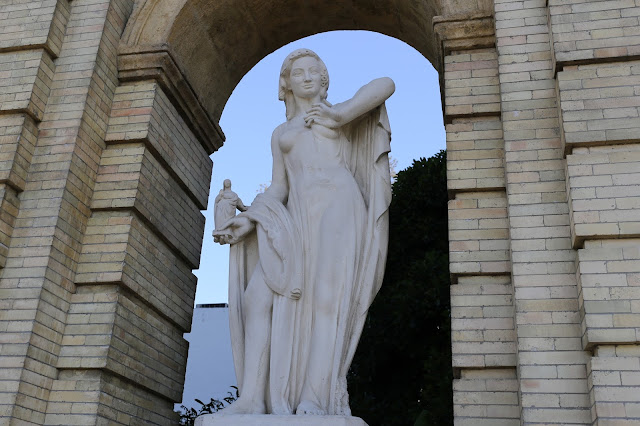 Estatua femenina bajo un arco.