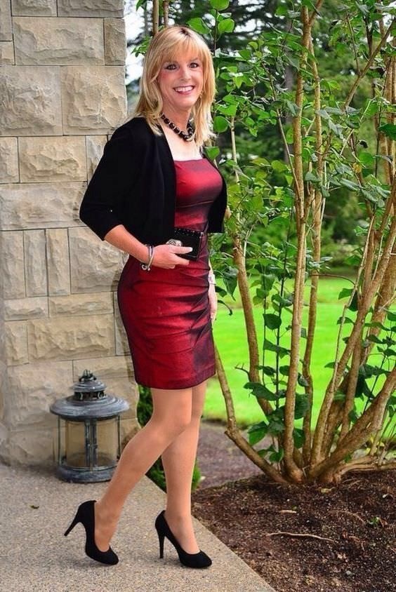 Beautiful crossdresser in red dress, pantyhose and high heels