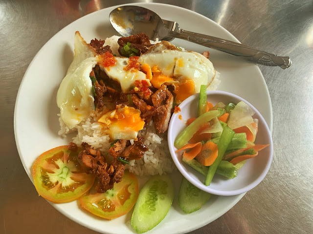 pork and rice with a fried egg, chili, and pickled vegetables in Cambodia