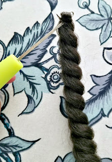 the crochet hook with the crochet hair inside the hook