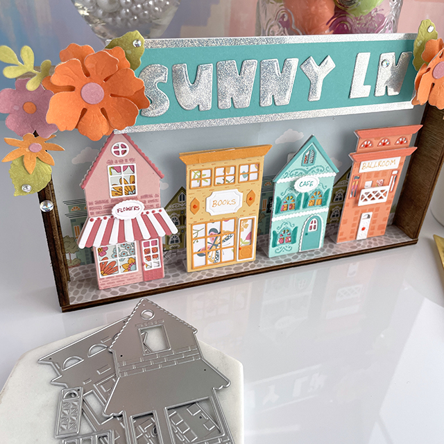 Sunny Lane Vignette created with: Scrapbook.com sunny lane houses, florals and paper, smooth cardstock, holographic paper, pops of color; Tim Holtz distress oxide; Pinkfresh clear drops iridescent