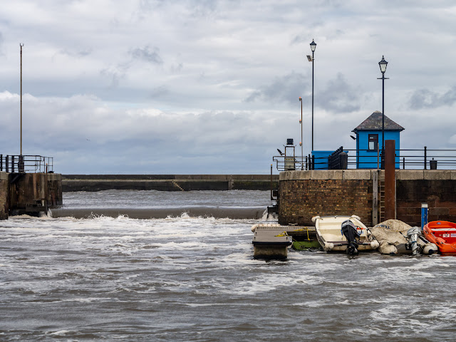 Photo of water pouring over the closed sea gate at Maryport Marina on Saturday