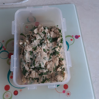 Rectangular tupperware container with a herby dough mix in it.
