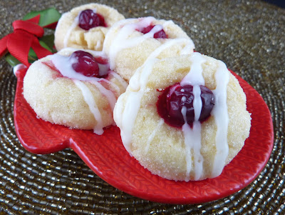 Cookies topped with a lemon glaze and a single cranberry. Photographed on a red mitten-shaped plate.