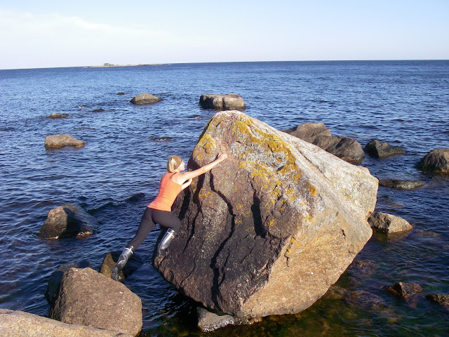siirtolohkare rannassa, ihminen kiipeää kivelle