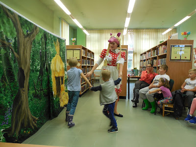 Scena z przedstawienia teatralnego, w której dzieci tańczą razem z postacią świnki.