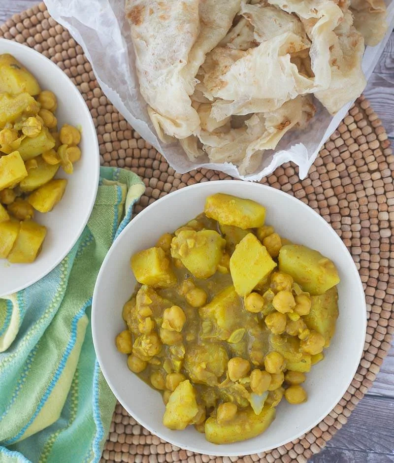 Curry channa and potato with roti skin served out in bowls.