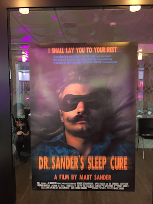 Haapsalu õudukafestivali koridorides. Lähivaade filmiplakatist "Dr Sandri uneravi". Plakatil on suures plaanis meesterahva nägu, mida ehivad suured vuntsid ja silmile tõmmatu unemask.