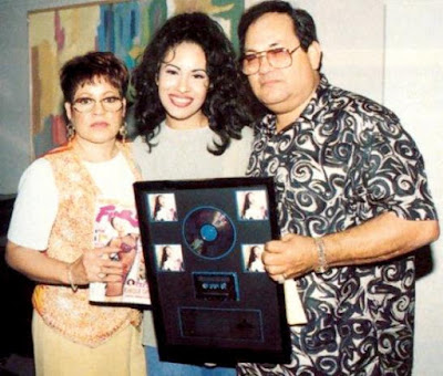 Selena feliz posando con su disco junto a su mamá y papá